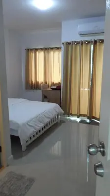a bedroom with a bed and a window with curtains at Little Home in Nonthaburi