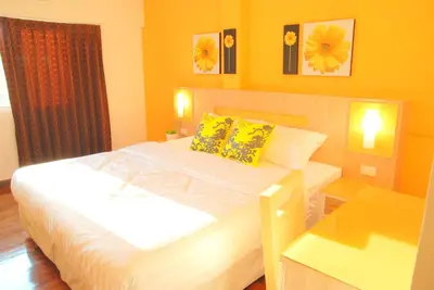 a bedroom with a large white bed with yellow walls at The Inn Saladaeng in Bangkok