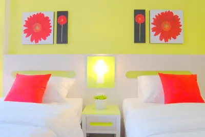 two beds in a bedroom with two red pillows at The Inn Saladaeng in Bangkok