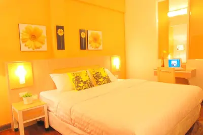 a bedroom with a white bed with yellow walls at The Inn Saladaeng in Bangkok