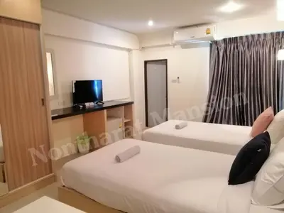 a bedroom with two beds and a tv in it at Nontharat Mansion in Nonthaburi