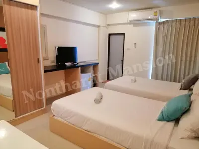 a room with two beds and a television in it at Nontharat Mansion in Nonthaburi