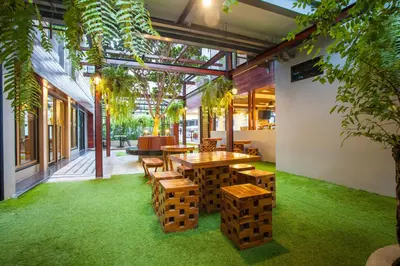 a restaurant with wooden tables and benches and green grass at New Siam Palace Ville Hotel in Bangkok