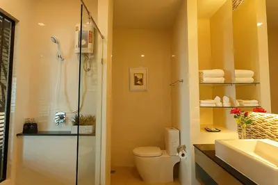 a bathroom with a shower and a toilet and a sink at Green Point Residence Hotel in Bangkok