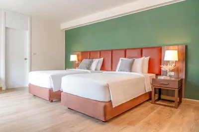 a large bedroom with two beds and a green wall at The Legacy Hotel Nana Sukhumvit, Aspira Collection in Bangkok