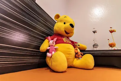 a yellow teddy bear sitting next to a bed at Bossotel Bangkok in Bangkok