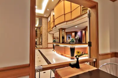 a dining room with a table and a mirror at Bossotel Bangkok in Bangkok