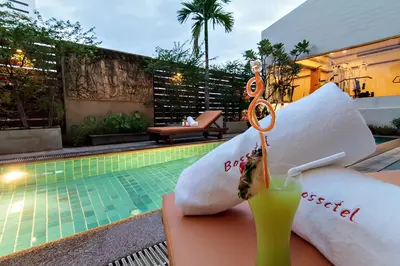 a drink sitting on a table next to a pool at Bossotel Bangkok in Bangkok