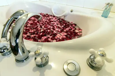 a bathroom sink with a bowl filled with pink confetti at Bossotel Bangkok in Bangkok
