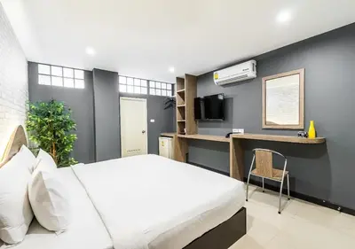 a bedroom with a white bed and a desk at Ton Aor Place Hotel in Bangkok