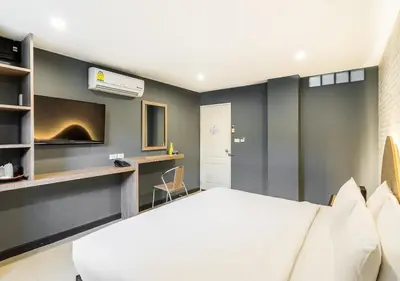 a bedroom with a large white bed and a tv at Ton Aor Place Hotel in Bangkok