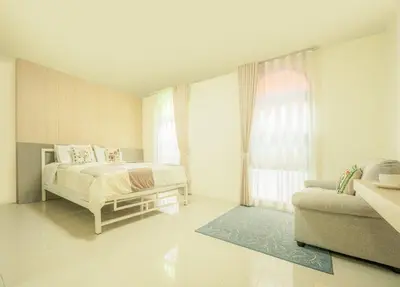 a white bedroom with a bed and a couch at Baansuanprannok Hotel in Bangkok