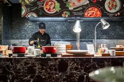 a chef preparing food in a restaurant kitchen at Renaissance Bangkok Ratchaprasong Hotel by Marriott in Bangkok
