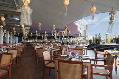 a dining room with tables and chairs and lights at Anantara Riverside Bangkok Resort in Bangkok