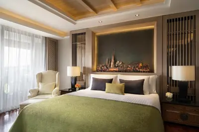 a bedroom with a large bed with a painting on the wall at Anantara Riverside Bangkok Resort in Bangkok
