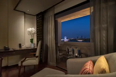 a living room with a fireplace and a couch and a window at Anantara Riverside Bangkok Resort in Bangkok