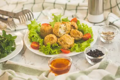 a plate of food with meatballs and salad on a table at Le Bonheur Poshtel in Bangkok