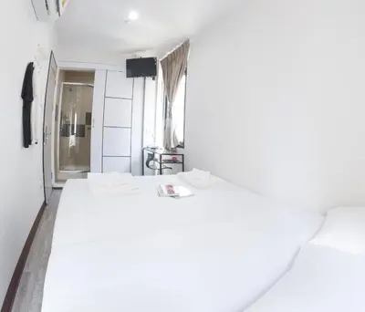 a room with two white beds and a window at Le Bonheur Poshtel in Bangkok
