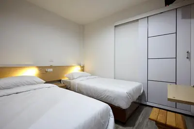 two beds in a hotel room with white sheets at Le Bonheur Poshtel in Bangkok