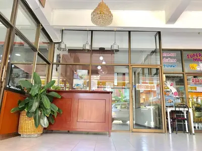 a store front with a red door and a potted plant at Tat Hotel in Bangkok
