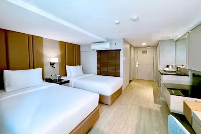 a hotel room with two beds and a kitchen at Ramada Sukhumvit Soi Eleven in Bangkok
