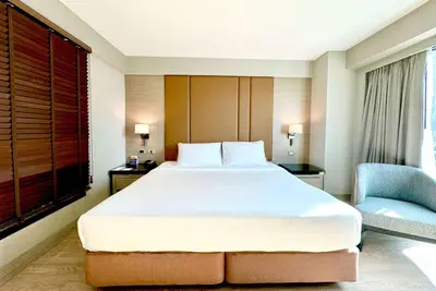 a bedroom with a large bed and a blue chair at Ramada Sukhumvit Soi Eleven in Bangkok
