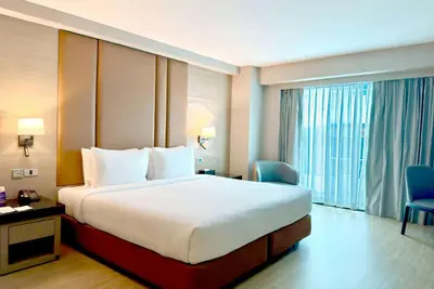 a hotel room with a bed and a large window at Ramada Sukhumvit Soi Eleven in Bangkok