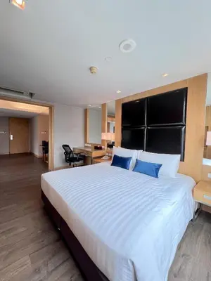 a large bedroom with a large bed with blue pillows at Sora Resort & Suites Sukhumvit in Bangkok
