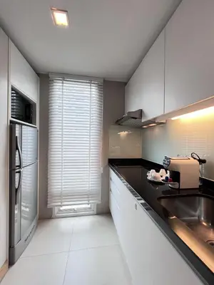 a kitchen with white cabinets and a black counter top at Sora Resort & Suites Sukhumvit in Bangkok