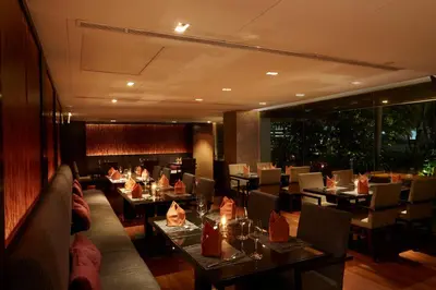 a restaurant with tables and chairs and a large window at Sora Resort & Suites Sukhumvit in Bangkok
