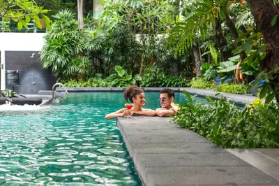 two people are sitting in a swimming pool at Sora Resort & Suites Sukhumvit in Bangkok