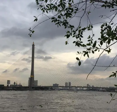 a suspension bridge over a river with a city at Hidden Lumpu in Bangkok