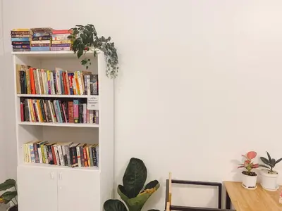 a book shelf filled with books next to a table at Pillow & Bread Hostel in Bangkok