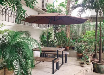 a table and bench with an umbrella in a courtyard at Pillow & Bread Hostel in Bangkok
