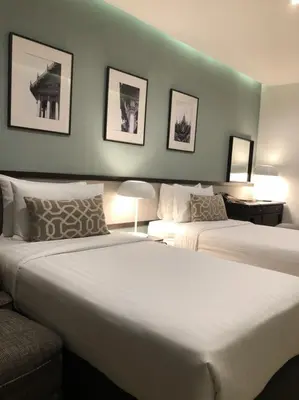 a hotel room with two beds and a green wall at Evergreen Place Siam by UHG in Bangkok