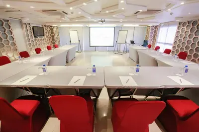 a conference room with white tables and red chairs at Northgate Ratchayothin in Bangkok
