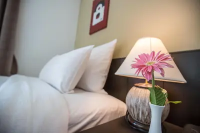 a flower in a vase on a table next to a bed at Northgate Ratchayothin in Bangkok