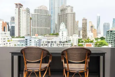 two chairs sitting at a table with a view of a city at SureStay Plus by Best Western Sukhumvit 2 in Bangkok