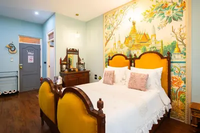 a bedroom with a bed with a painting on the wall at The Unforgotten B&B in Bangkok