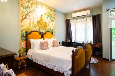 a bedroom with a large bed with a painting on the wall at The Unforgotten B&B in Bangkok