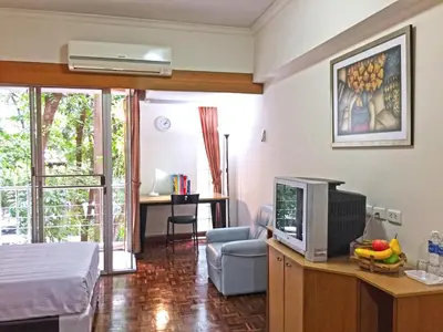a living room with a tv and a room with a couch at Rio Monte Residence in Bangkok