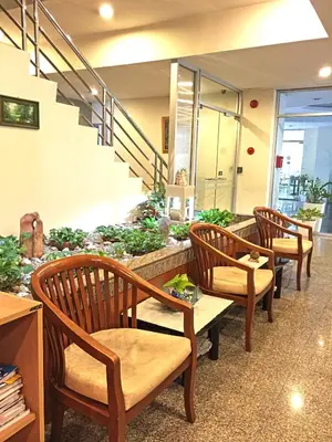 a waiting area with three wooden chairs and a garden at Rio Monte Residence in Bangkok