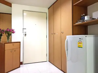 a kitchen with a white refrigerator and wooden cabinets at Rio Monte Residence in Bangkok
