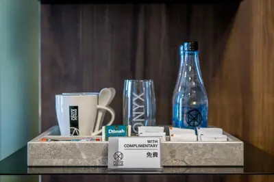 a shelf with cups and a glass bottle on it at Onix Hotel Bangkok in Bangkok