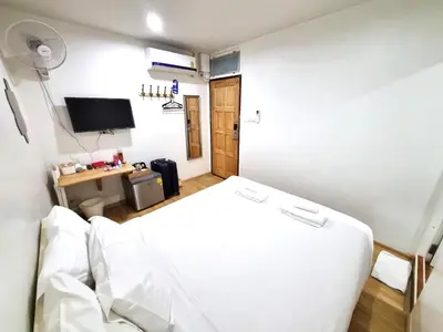 a bedroom with a white bed and a television at K Home Asok in Bangkok