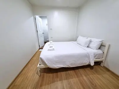 a small white bedroom with a bed with white sheets and pillows at K Home Asok in Bangkok