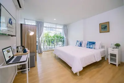 a bedroom with a bed and a desk with a laptop at K Home Asok in Bangkok