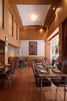 a dining room with wooden tables and chairs at KC Place Hotel Pratunam in Bangkok