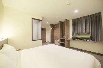 a bedroom with a large white bed and a television at Sovereign Group Hotel at Pratunam in Bangkok