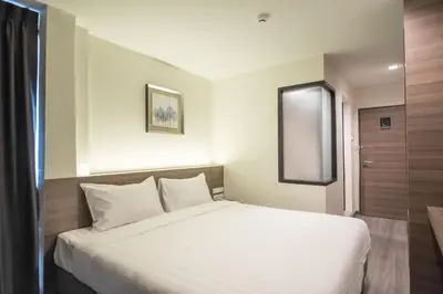 a bedroom with a white bed and a window at Sovereign Group Hotel at Pratunam in Bangkok
